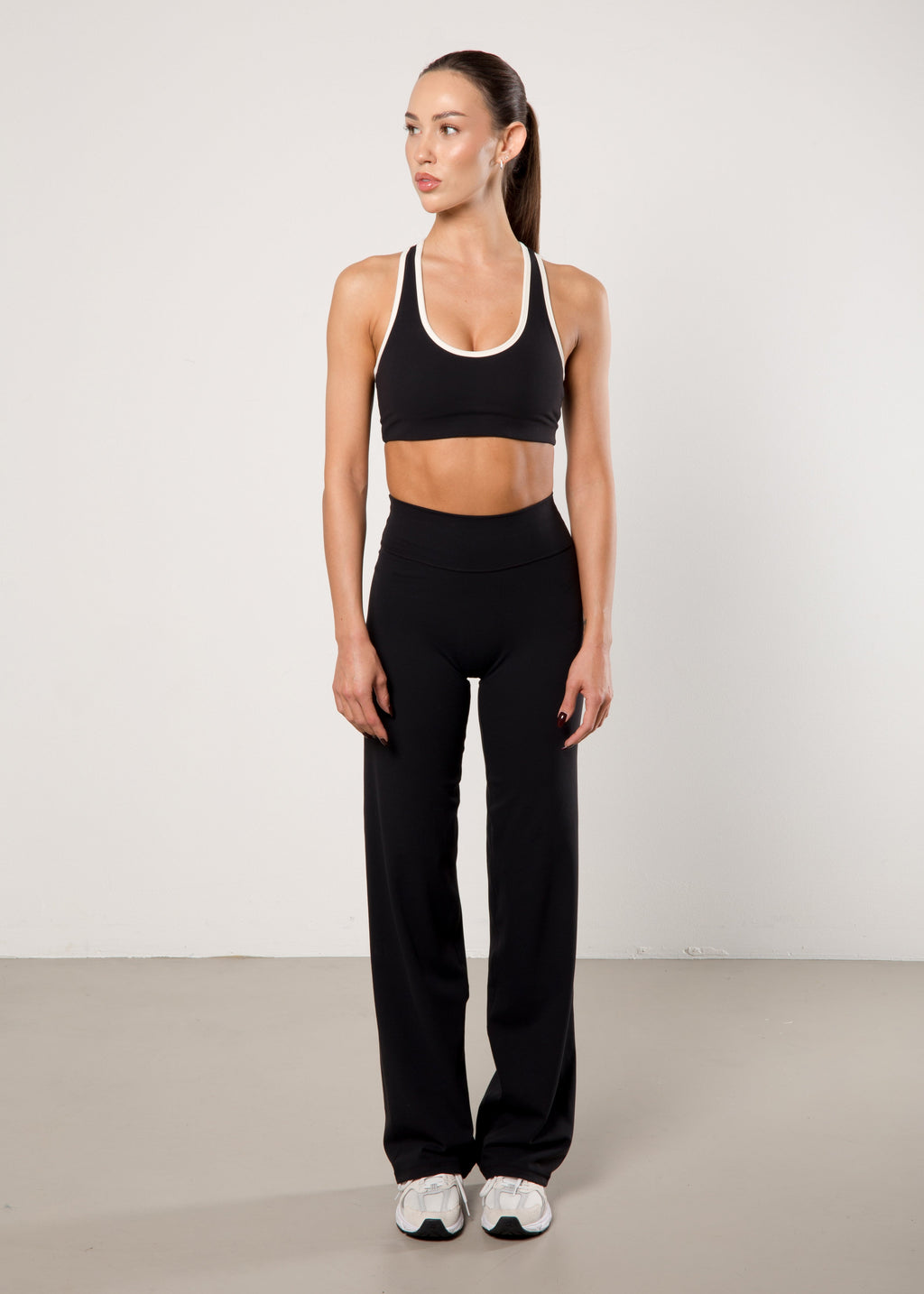 Woman wearing a black sports bra and leggings set on a plain background